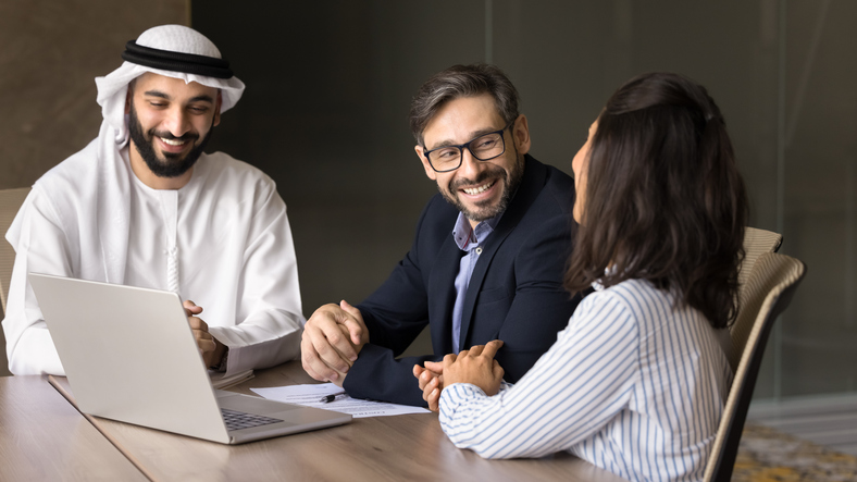 Happy Arabian businessman, company owner in traditional Muslim dress meeting oversea clients selling company services